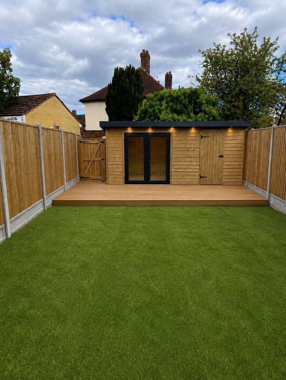 Panel fencing down both sides of a lawn, with a deck and garden room at the end