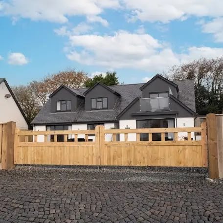 Low timber driveway gates and matching fence in front of a house